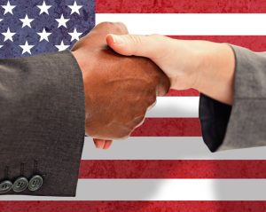 Business people shaking hands in front of US flag